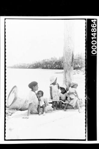 A woman and several children sit on a Galapagos Island beach