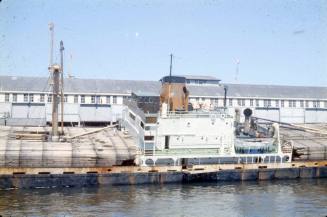 Slide depicting a fully loaded cargo vessel docked alongside a wharf