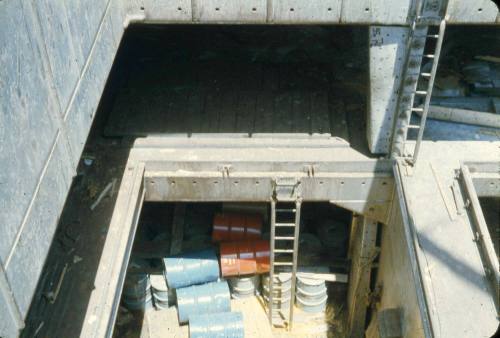 Slide of the cargo hold with loose blue and orange drums at the bottom