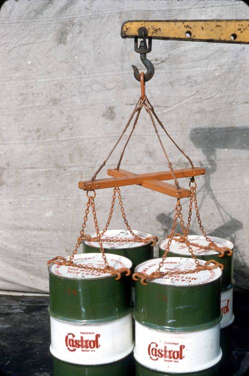 Slide depicting four barrels with chains being loaded, barrels read castrol