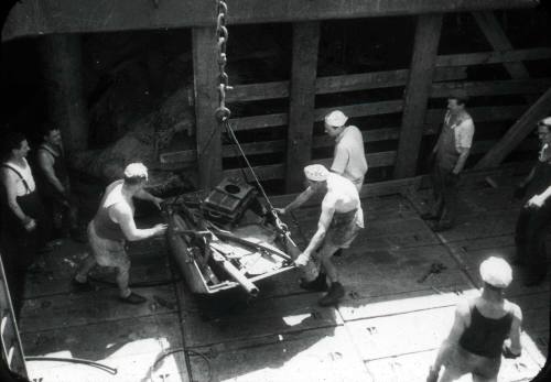 Slide depicting men loading material into a skip