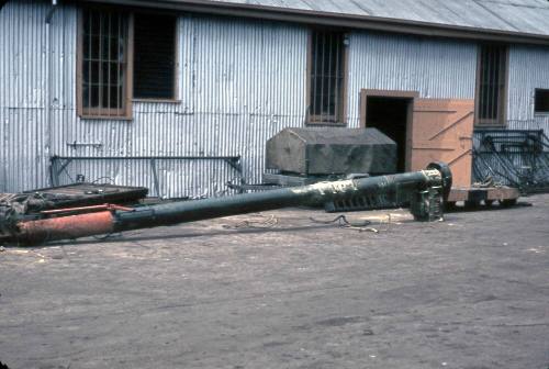 Slide depicting a metal pole lying on the ground in front of a blue shed