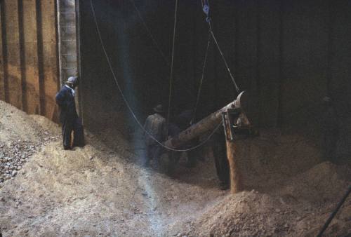 Slide depicting men in the cargo hold with mountains of coal or sand visible