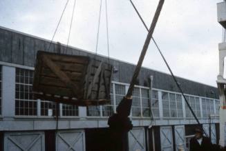 Slide depicting crate being lifted via crane on a vessel