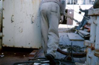 Slide depicting man standing amist a coil of ropes