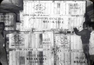 Slide depicting a stack of wooden crates containing glass