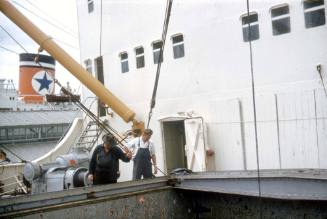 Slide depicting two men looking down a hatch on deck