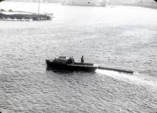 Slide depicting boat towing large wooden log in water