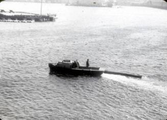 Slide depicting boat towing large wooden log in water