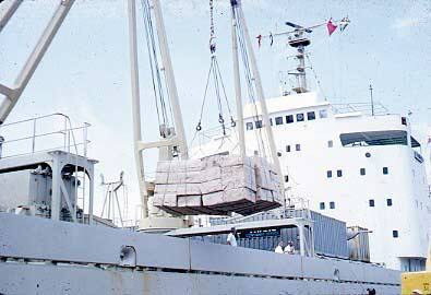 Slide depicting a boxed cargo being transported off ship by crane