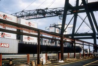 Slide depicting wharfside looking up to containers being loaded onto ship