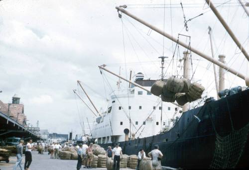 Slide depicting bundled cargo being taken on or off ship by crane