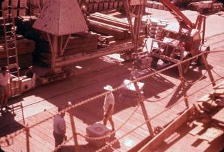 Slide depicting two boxes bound by rope affixed to crane on wharf side