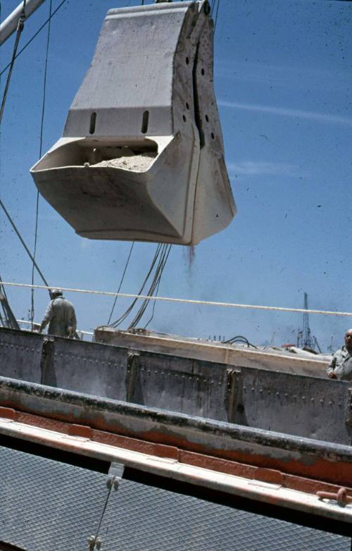 Slide depicting the moving of gravel onto a ship for transport