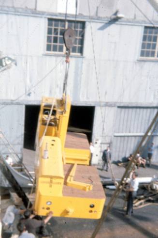 Slide depicting canvas shrouded cargo being lifted onto a ship