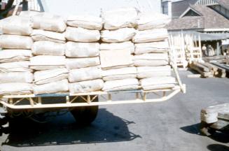 Slide depicting a stack of sacks on a pallet being lifted from above