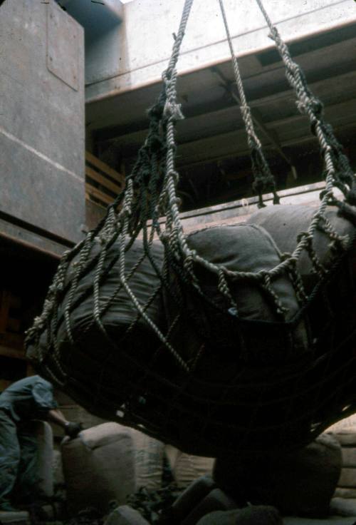 Slide depicting large hessian bags in netting being bundled and lifted