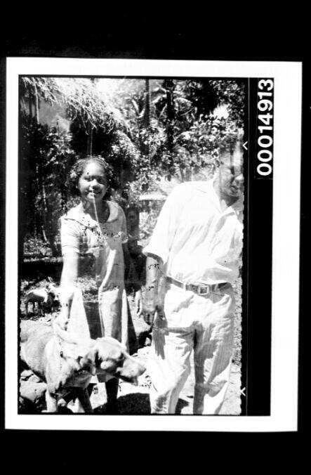 A young girl restrains her dog for a photo in a village, Fatu Hiva Island