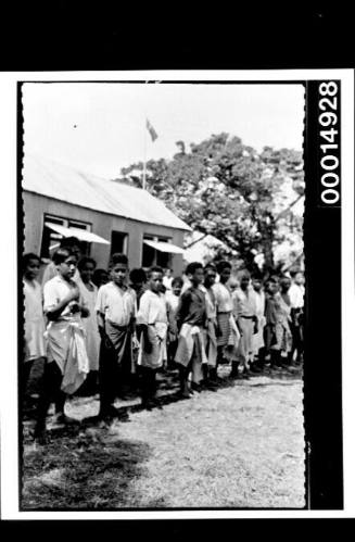 Children line up in an orderly fashion along a building, Nuku'alofa, Tonga
