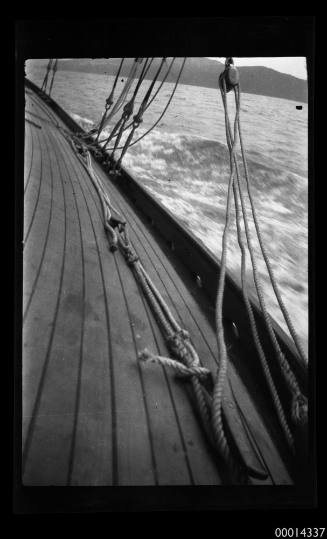 The deck of a wooden yacht under sail off the coast