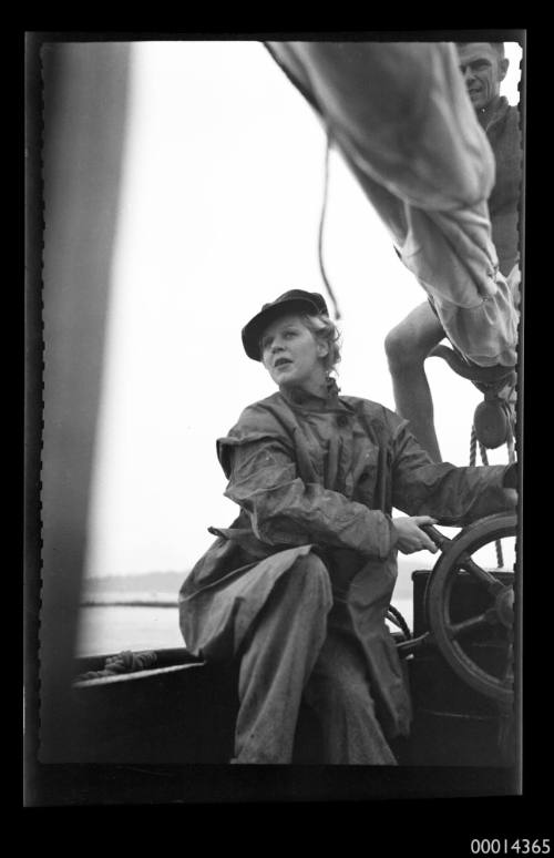 Young woman steering yacht under sail