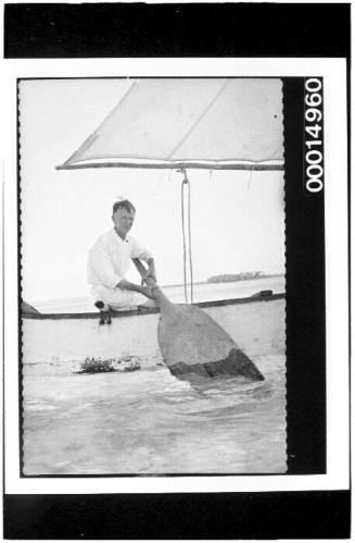 Harold Nossiter Snr holding a wooden paddle aboard a sailing craft, Bora Bora