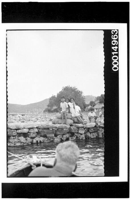 Children watch from a stone wharf's edge, Bora Bora