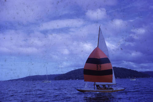 Image of sailing boat with red and black sail