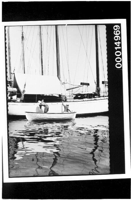 Two men working on the hull of the yacht SIRIUS from a dinghy in Tahiti