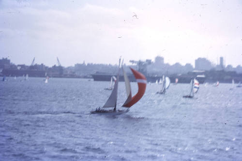 Image of yacht with red spinnaker sailing on Sydney Harbour