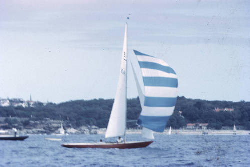 Sailboat under sail with spinnaker with blue and white stripes