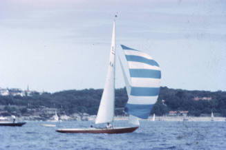 Sailboat under sail with spinnaker with blue and white stripes