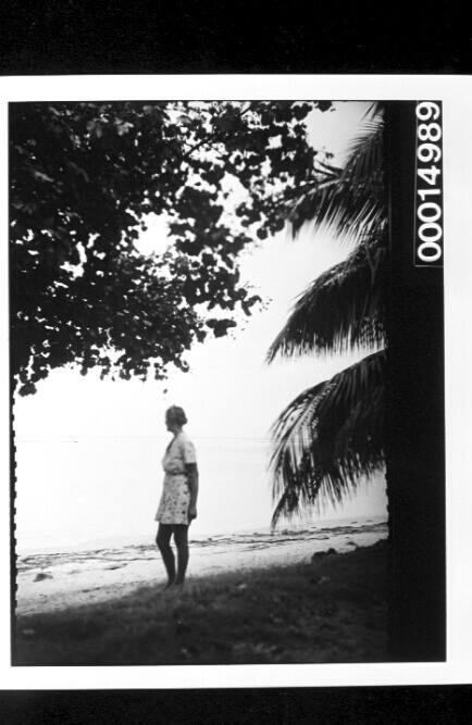 A woman stands on a Tahitian beach looking toward the sea