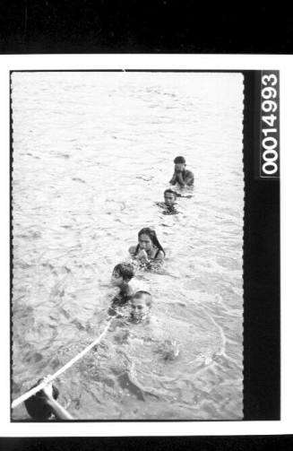 Children from Rarotonga play on a rope in the sea