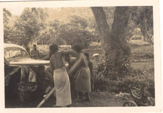 Photograph depicting a group of men looking at a car