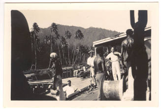 Photograph depicting men working at a dock in a tropical landscape
