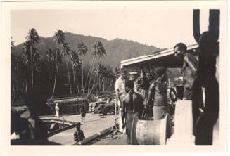 Photograph depicting men working at a dock in a tropical landscape