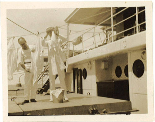 Photograph depicting two men hanging the washing on board a vessel