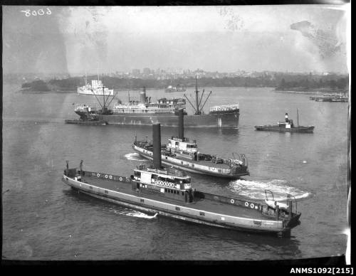 Ferries KALANG, KOONDOOLOO underway with a warship (possibly HMAS CANBERRA) and HMAS ANZAC at anchor, Sydney Harbour