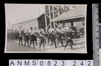 Silver gelatin photograph depicting marching brass band in street during ceremony