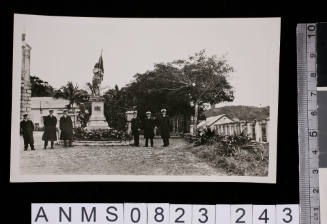 Silver gelatin photograph of six uniformed men standing beside statue