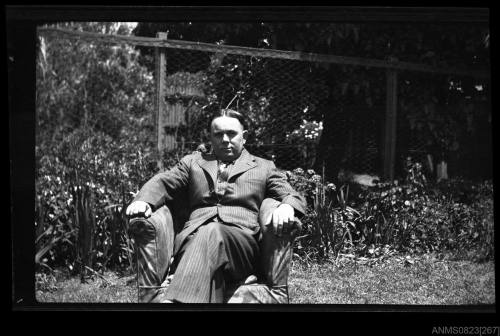 Photographic negative of a man seated in a garden