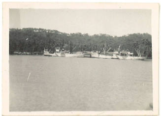 Photograph depicting two vessels moored alongside wharf buildings on tropical island