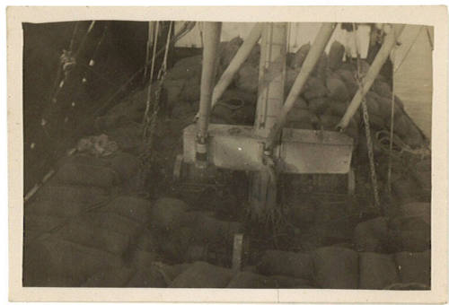 Photograph depicting cargo of sacks piled on deck of a ship