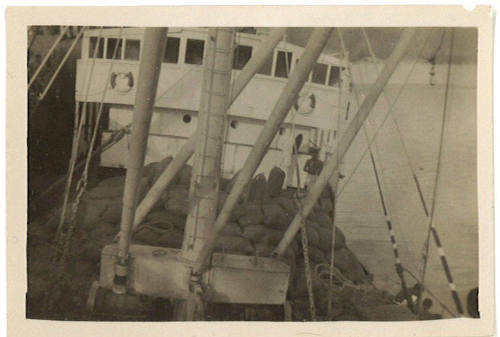 Photograph depicting cargo of sacks piled on deck of a ship