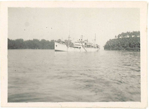 Photograph depicting a vessel in channel of water between two tropical islands