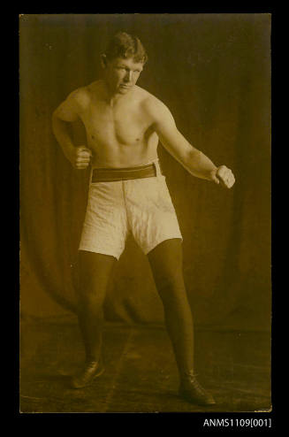 Photographic postcard of a boxer standing with clenched fist