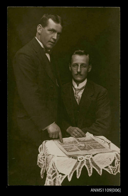 Photographic postcard of two men at a small table reading a 'The Daily Mirror' newspaper