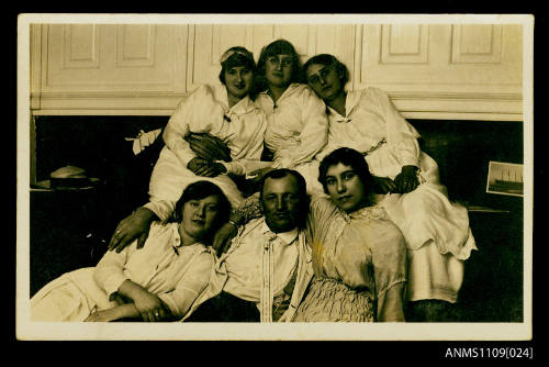 Photographic postcard of a man and five women