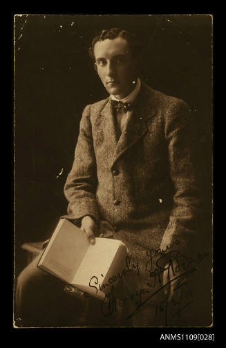 Signed photographic postcard of a young man holding a book